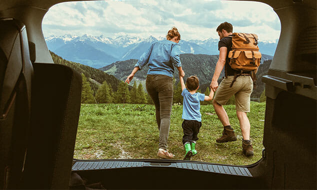 view out the back of an SUV of a young family going for a hike