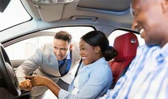 car salesman showing woman features of new car