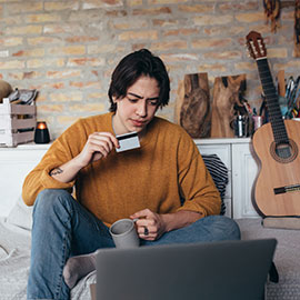 young person holding credit card and looking at computer