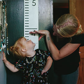 mom measuring height of daughter on the wall