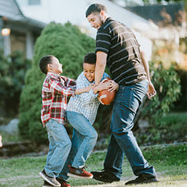 father and sons playing football