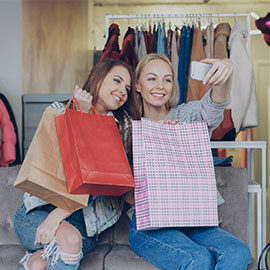 two girls taking a selfie with shopping bags